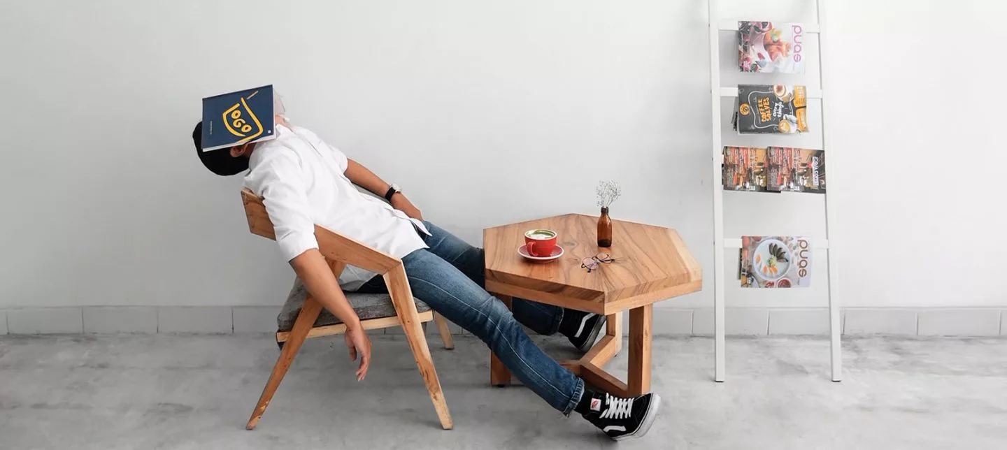 person leaning back in a chair with a book over their face