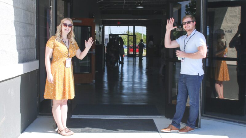 people waving at a building entrance