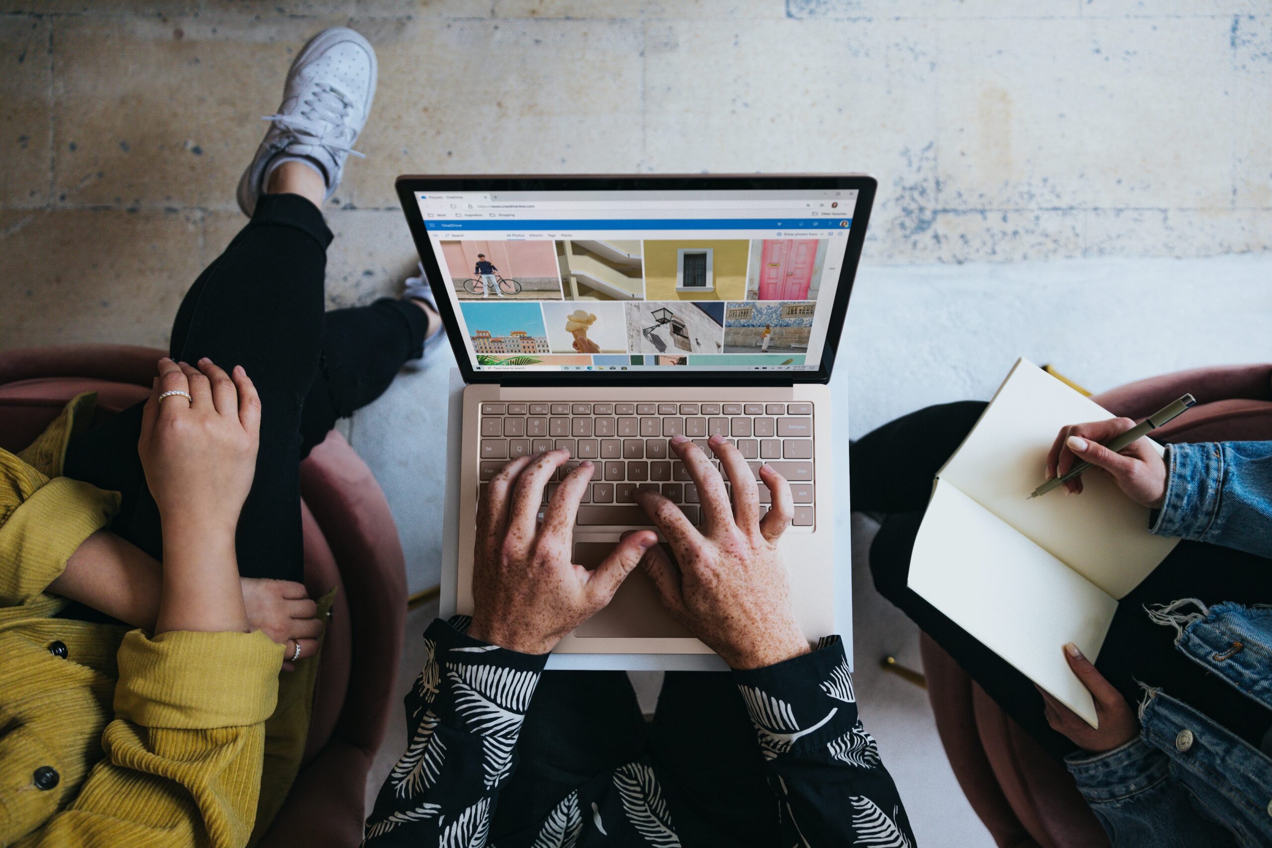 person using laptop sitting in between two co-workers
