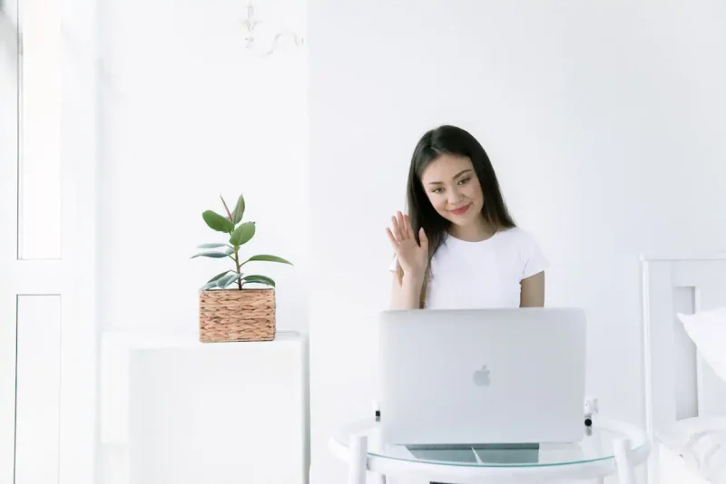 Woman onboarding and offboarding remotely,  waving at laptop